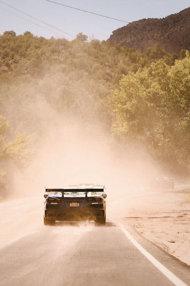 A winged race car disappears into a wall of desert dust