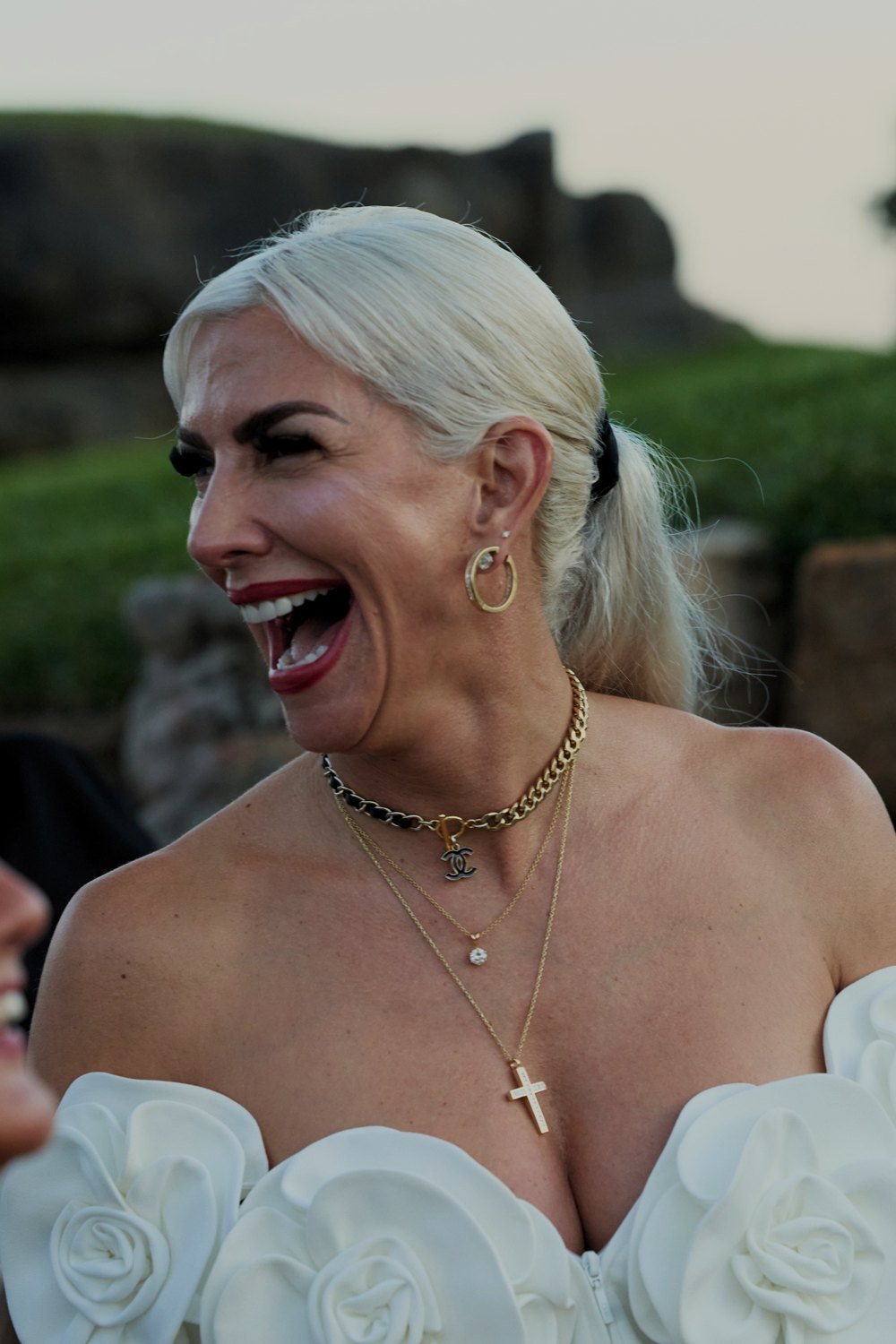 A guest in a white dress laughs at the evening party