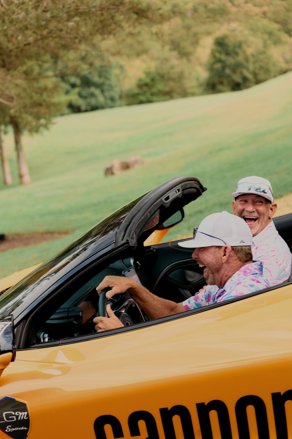 Driver and co-driver laugh as they roll out in an orange Cannonball convertible