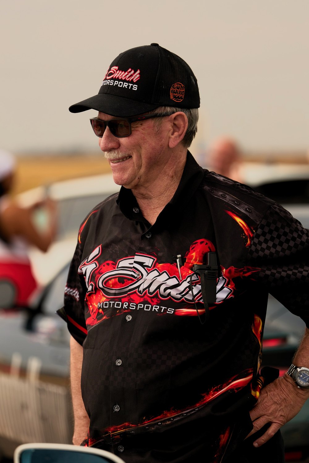 A driver in a G. Smith Motorsports jacket and cap