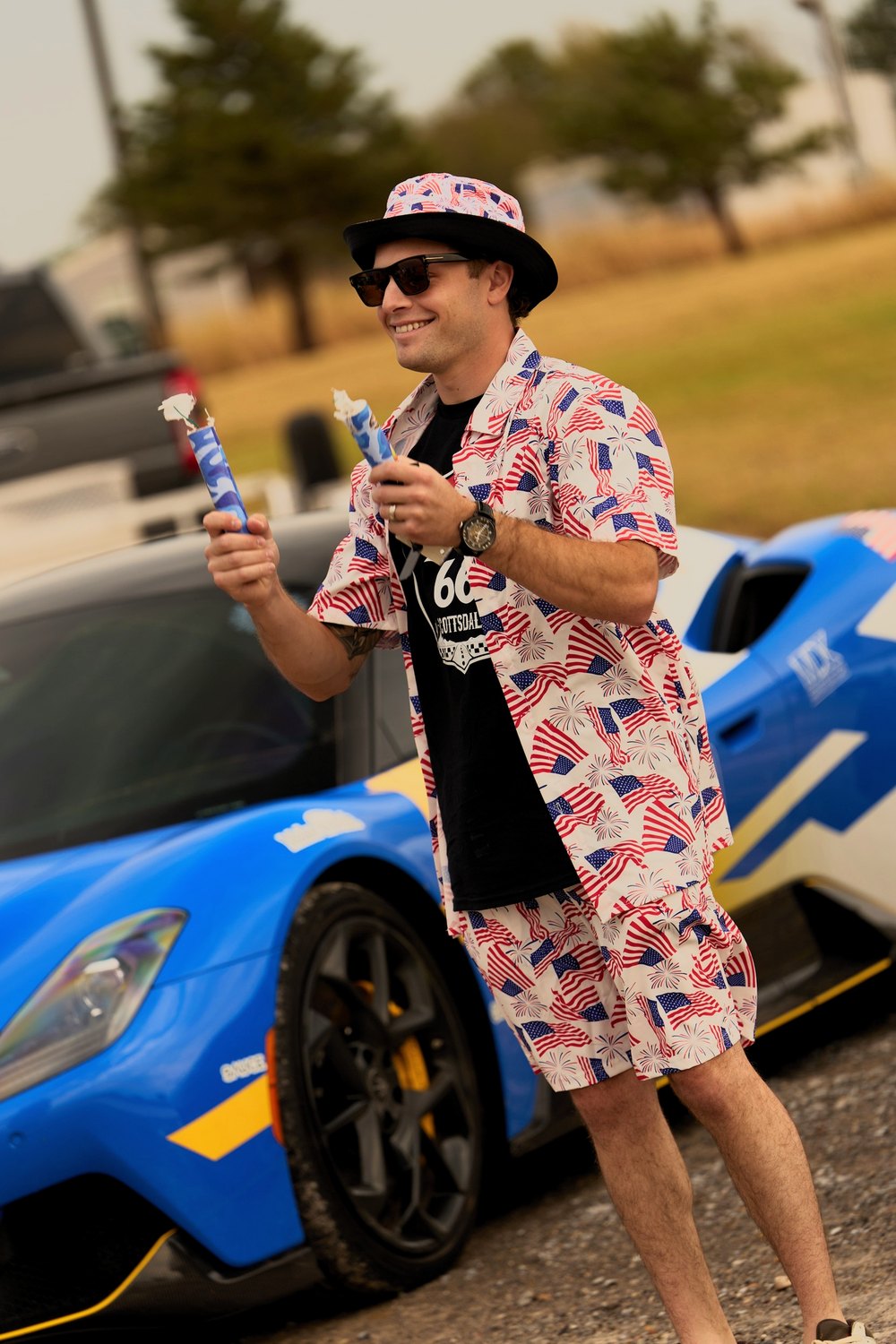 A driver in a stars-and-stripes suit hands out ice pops by a blue Cannonball car