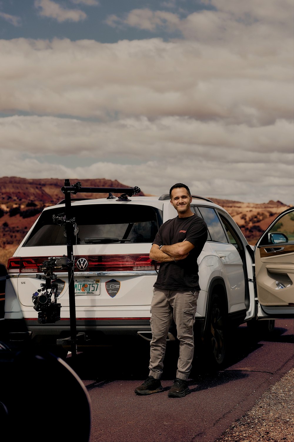 A photographer stands by his camera car, the rig mounted on its tail, in the desert