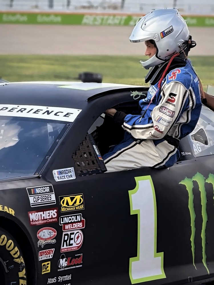 A driver climbs out of the black number 1 stock car on pit road